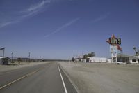 a street in an area of desert with motel signs on the side and a desert road behind