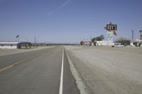 a street in an area of desert with motel signs on the side and a desert road behind