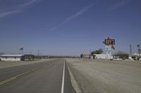 a street in an area of desert with motel signs on the side and a desert road behind