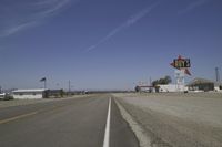 a street in an area of desert with motel signs on the side and a desert road behind