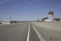 a street in an area of desert with motel signs on the side and a desert road behind