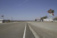 a street in an area of desert with motel signs on the side and a desert road behind