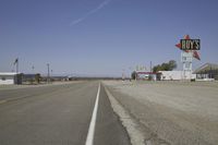 a street in an area of desert with motel signs on the side and a desert road behind