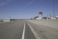 a street in an area of desert with motel signs on the side and a desert road behind