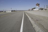 a street in an area of desert with motel signs on the side and a desert road behind