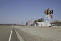 a street in an area of desert with motel signs on the side and a desert road behind