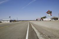 a street in an area of desert with motel signs on the side and a desert road behind