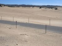 a paved beach with a fence in front of it and the ocean in the distance