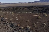 large and small rocks in the middle of the desert landscape with large rocky mountains in the background