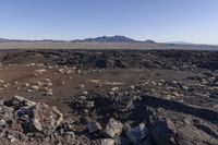 large and small rocks in the middle of the desert landscape with large rocky mountains in the background