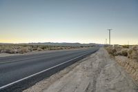 a lone street that is empty in the desert on a sunny day from the point where the road has not yet been paved