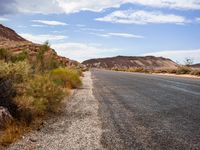 the sign is on a deserted country road near some cliffs in the desert at the roadside