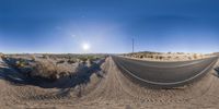 a wide angle view of a deserted road surrounded by trees and shrubbery in the desert