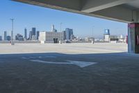 an empty parking lot with city skyline in background from the bottom level of a building