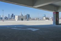 an empty parking lot with city skyline in background from the bottom level of a building