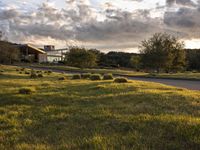 a dirt road that leads to a grassy area and a home with trees on it