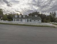 an older house with a large white picketer fence along the front yard and garage area