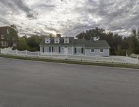 an older house with a large white picketer fence along the front yard and garage area