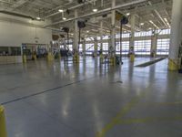 a large warehouse with various equipment on the floor and yellow pillars and doors in the middle of it