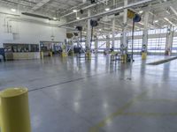 a large warehouse with various equipment on the floor and yellow pillars and doors in the middle of it