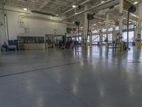 a large warehouse with various equipment on the floor and yellow pillars and doors in the middle of it