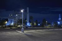 a nighttime parking lot with a factory in the background at night time with multiple lights