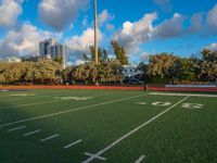 an empty football field with several players running in it and a view of buildings and trees