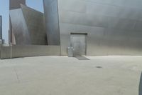 a person riding a bike in front of an art museum that includes metallic walls and some steps