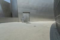 a person riding a bike in front of an art museum that includes metallic walls and some steps