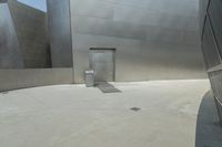 a person riding a bike in front of an art museum that includes metallic walls and some steps