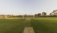 a soccer goal sits in a soccer field by the tennis fields at a nearby school