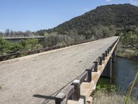 a view from a bridge overlooking trees and a mountain range of hills behind a bridge