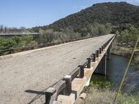 a view from a bridge overlooking trees and a mountain range of hills behind a bridge