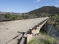 a view from a bridge overlooking trees and a mountain range of hills behind a bridge