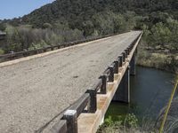 a view from a bridge overlooking trees and a mountain range of hills behind a bridge