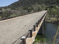 a view from a bridge overlooking trees and a mountain range of hills behind a bridge