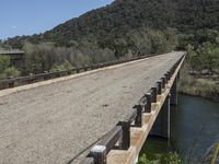 a view from a bridge overlooking trees and a mountain range of hills behind a bridge