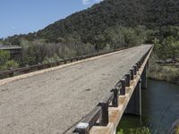 a view from a bridge overlooking trees and a mountain range of hills behind a bridge