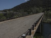 a view from a bridge overlooking trees and a mountain range of hills behind a bridge