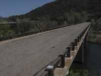 a view from a bridge overlooking trees and a mountain range of hills behind a bridge