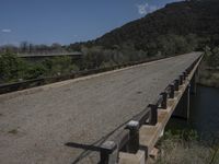 a view from a bridge overlooking trees and a mountain range of hills behind a bridge