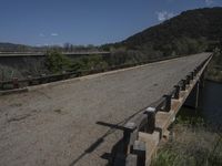 a view from a bridge overlooking trees and a mountain range of hills behind a bridge