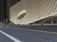 the street is deserted in front of a large building with an angled facade and many windows