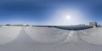 a cityscape shot taken on a 360 camera and fisheye lens with an empty parking lot and lots of vehicles