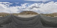 a view of a road in the middle of nowhere with no people around it and mountains, like a desert