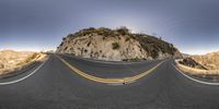 a road that is winding into a mountain with a couple of arches above it on the side