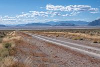 the road is wide and empty in a vast terrain landscape with mountains in the distance