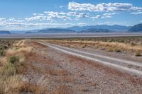 the road is wide and empty in a vast terrain landscape with mountains in the distance