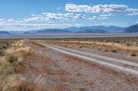 the road is wide and empty in a vast terrain landscape with mountains in the distance