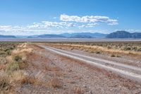 the road is wide and empty in a vast terrain landscape with mountains in the distance